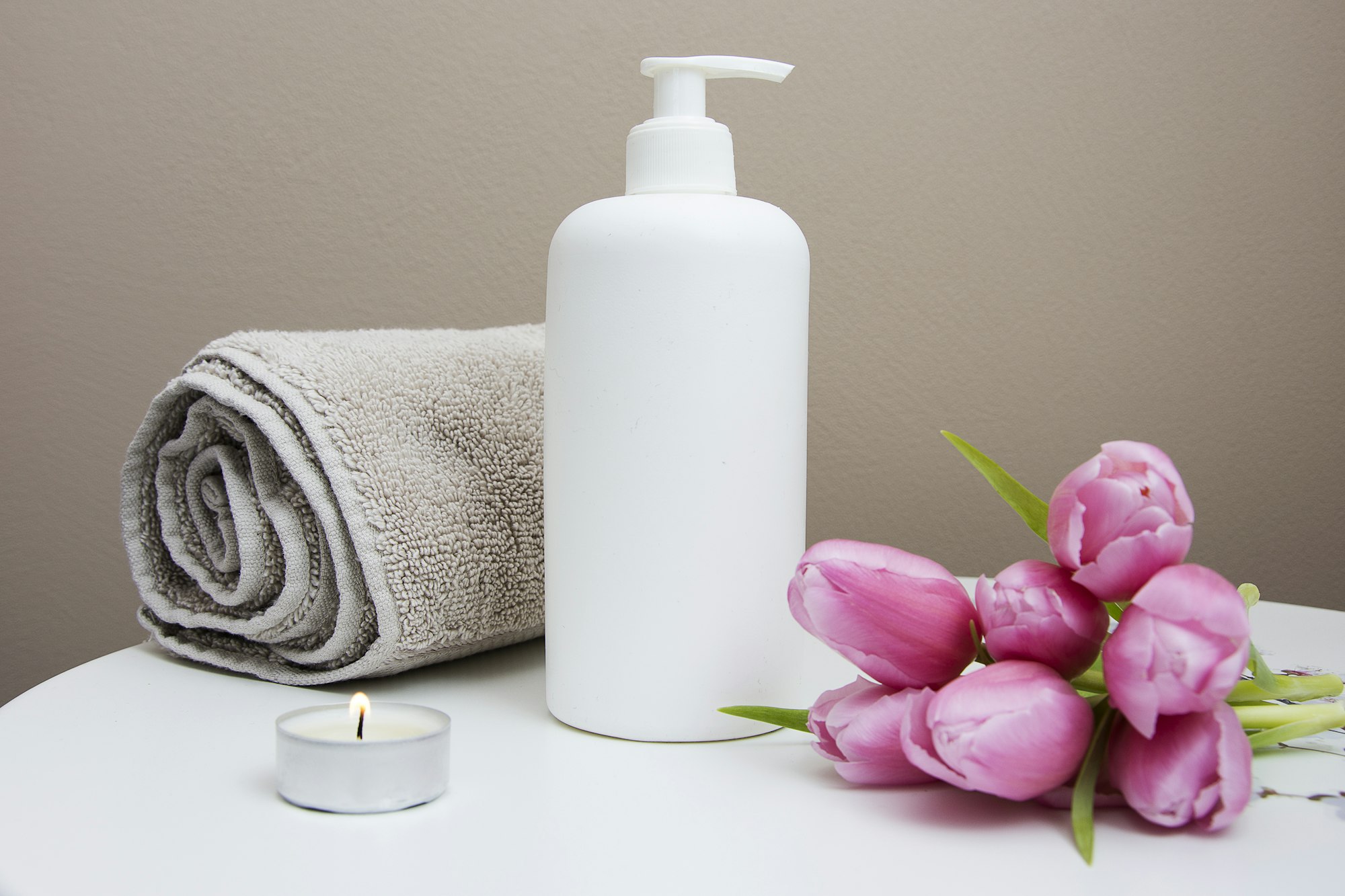 Rolled towel, candle and pink tulips