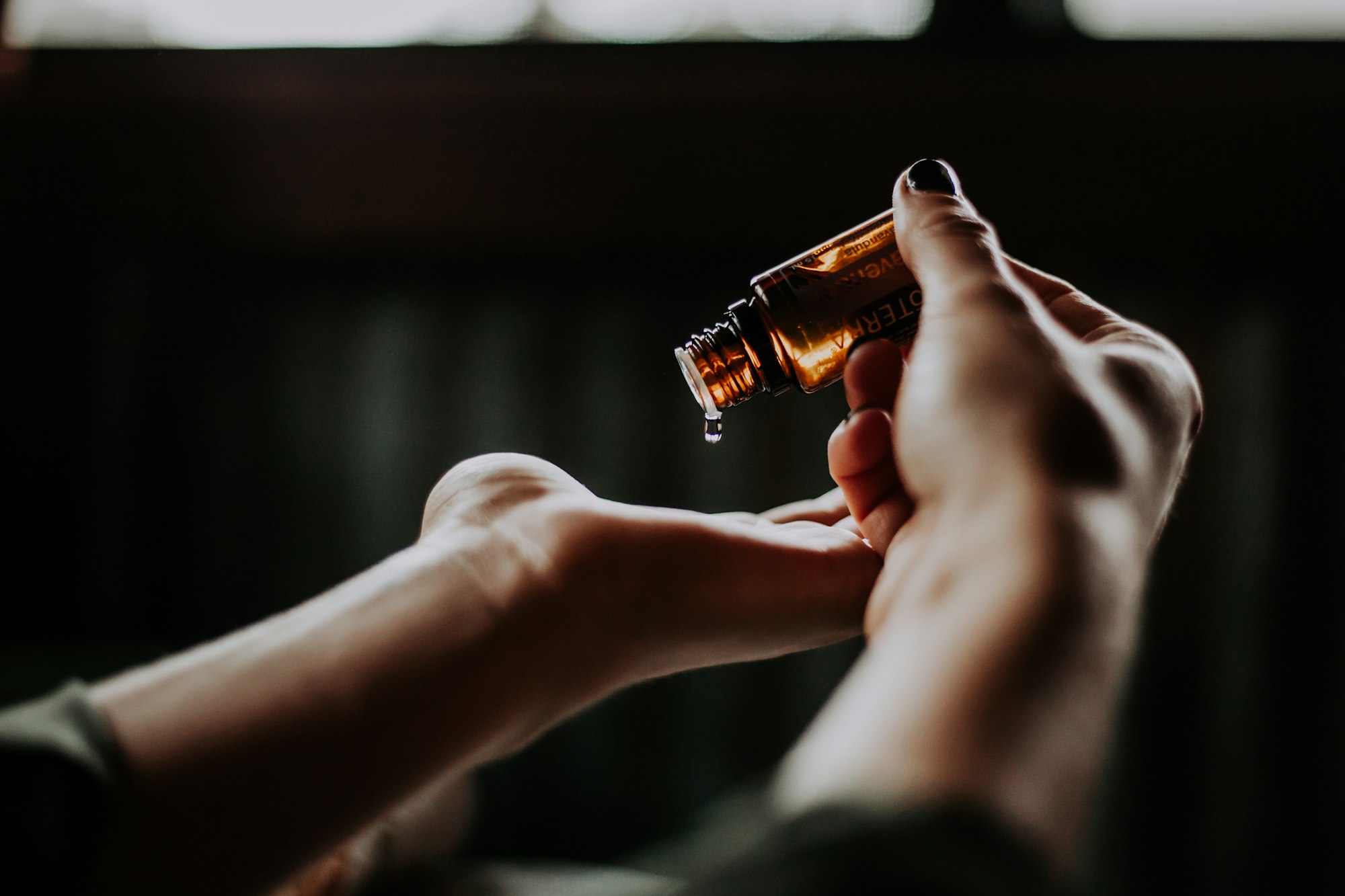Therapist's hands warming a drop of massage oil